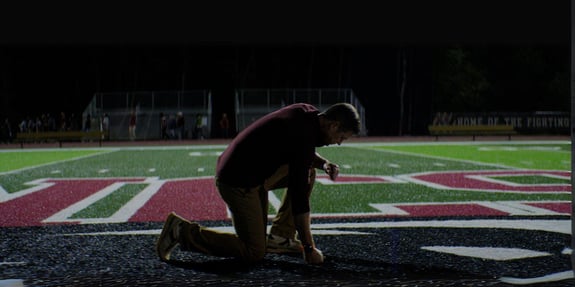 average joe coach kneeling on field